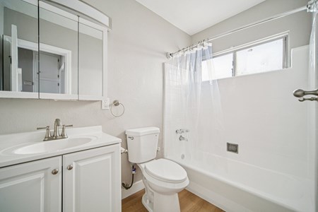 A white bathroom with a toilet, sink, and bathtub.